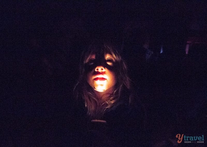 girl holding flashlight under chin