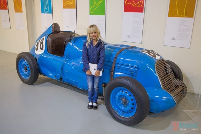 girl standing in front of a race car