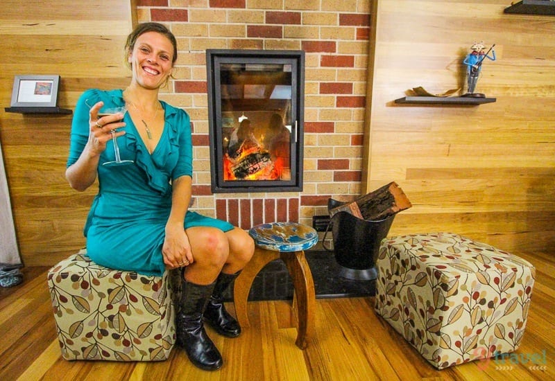 woman sitting on chair with glass of red wine by the fire