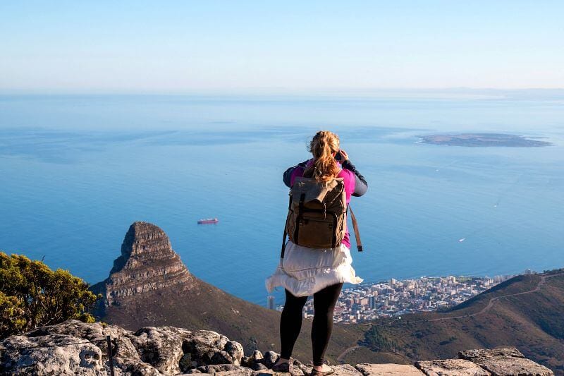girl standing on table mountain taking a photo of the view