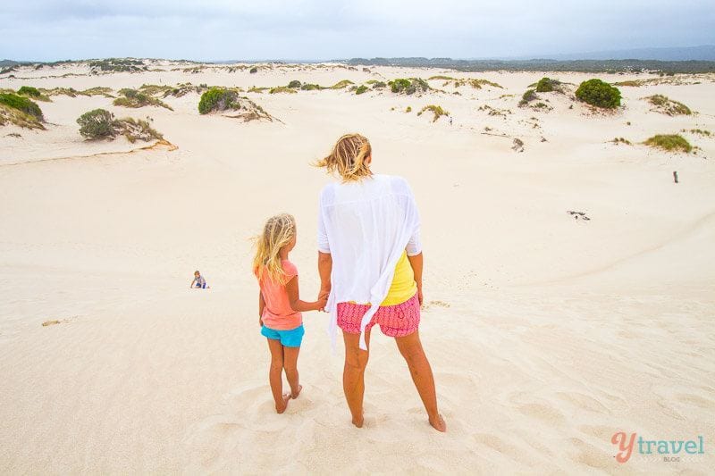 woman and child standing on sand dunes