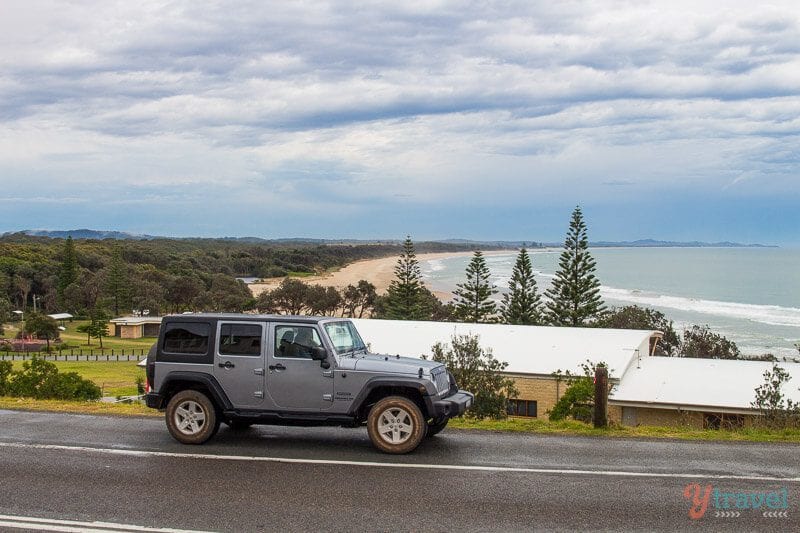 jeep on side of road with Rainbow Beach, in the background