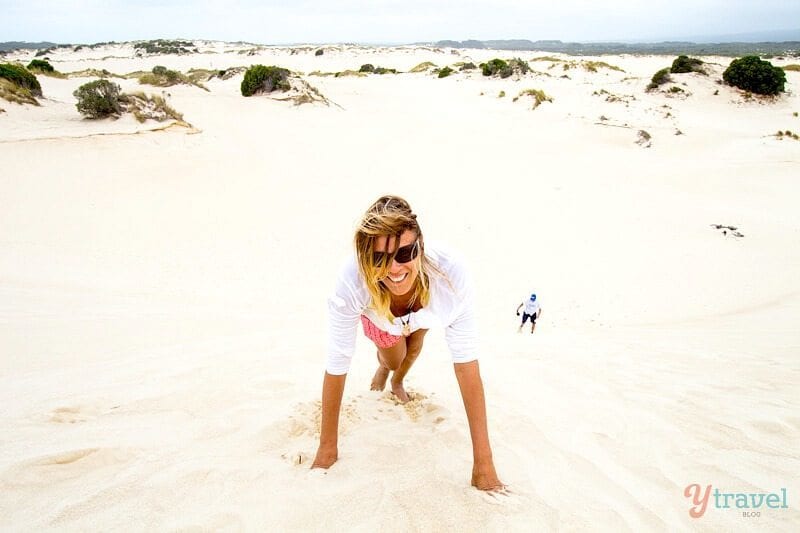woman climbing up a sand dune