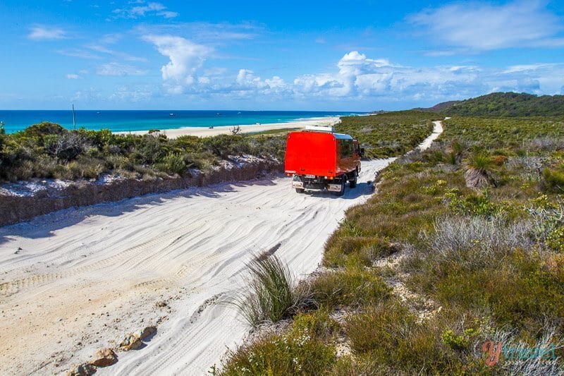red truck driving on sand on Moreton Island, Queensland, Australia
