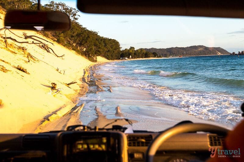 car driving on the beach with water rushing up
