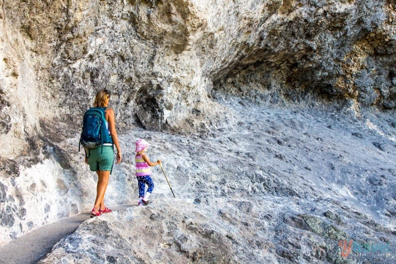 woman and young girl on a rocky path through a mountain