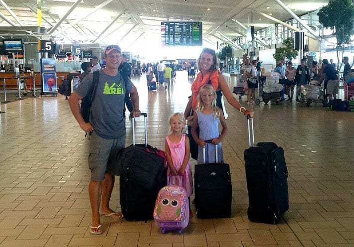 family posing at airport with luggage