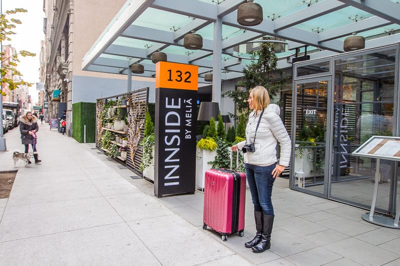 woman standing with suitcase outside innside new york nomad