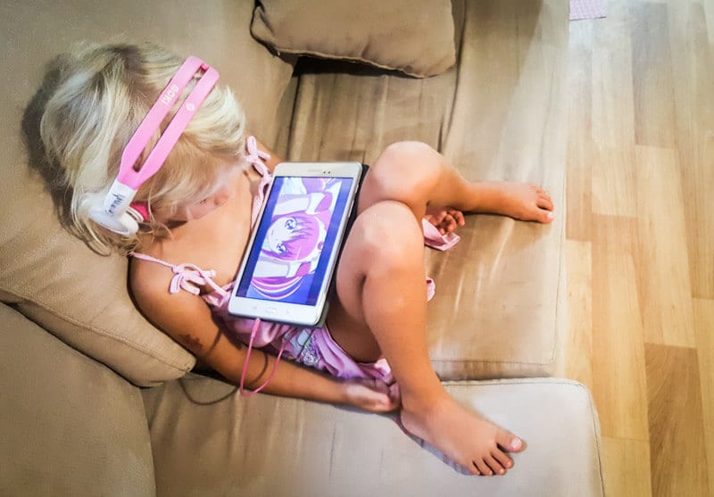 chid on couch watching ipad with headphones on