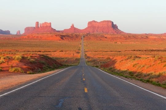 road leading towards rocky mountains in the desert