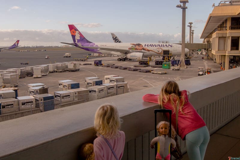 twi girls looking at hawaiian airplane at gate