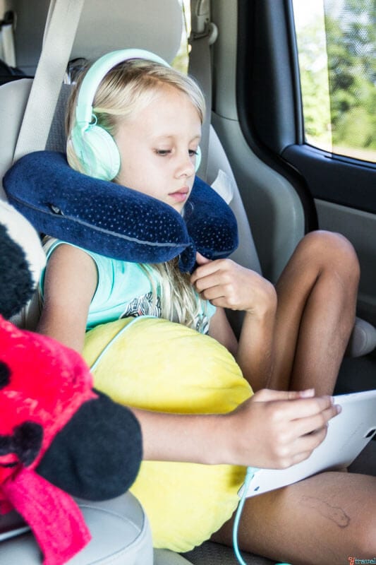 girl using neck pillow and headphones in car