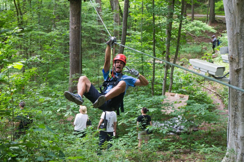 man on zipline giving peace sign The Navitat Canopy Experience