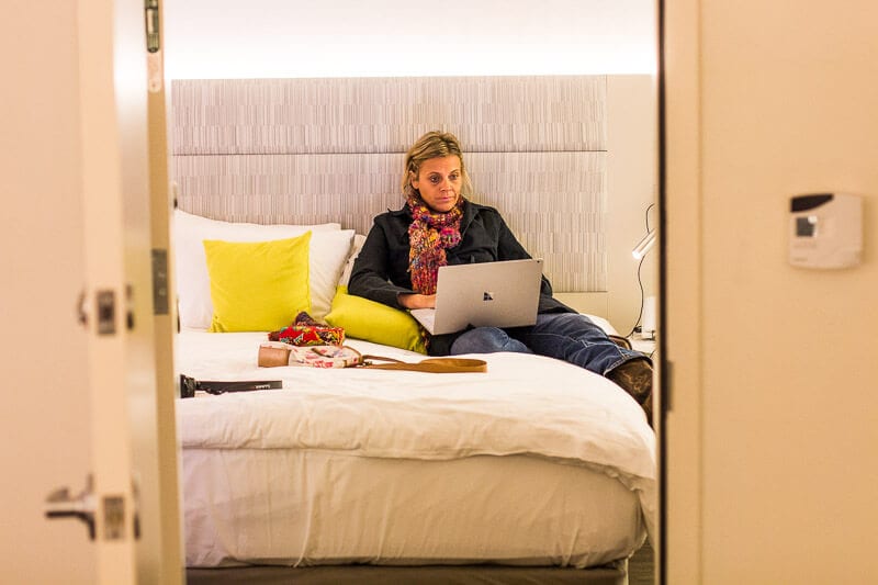 woman on laptop sitting on hotel bed