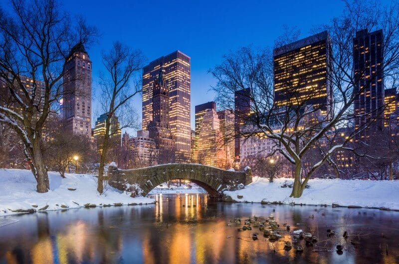 bridge over pond in central park with snow over it