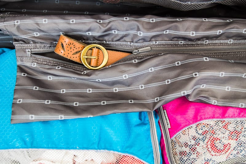 belt sticking out of pocket inside suitcase