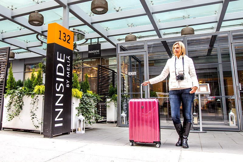 caz standing outside of hotel with rolling suitcase