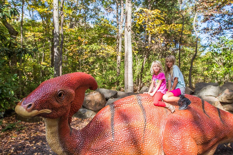 two girls sitting on a dinosaur sculpture