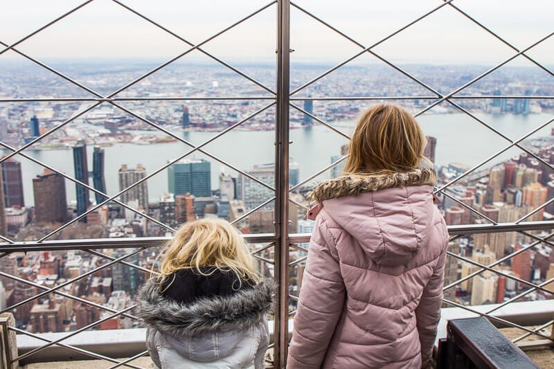 tow girls looking at the views of Manhattan from Empire State Building 