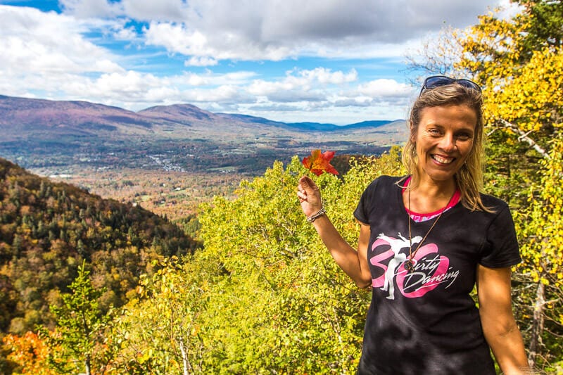 woman holding red leaf with valley views on the Prospect Rock Trail, Vermont