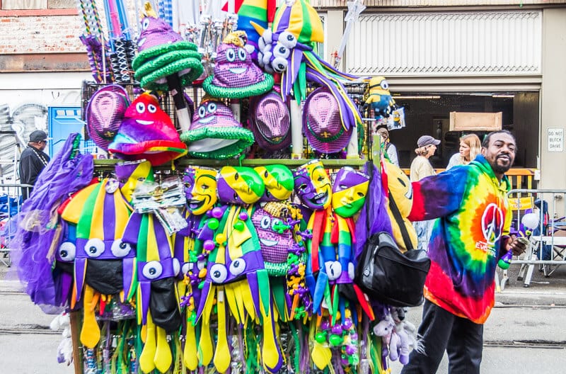 man pulling cart with purple green and gold hats and scarves for mardi gras