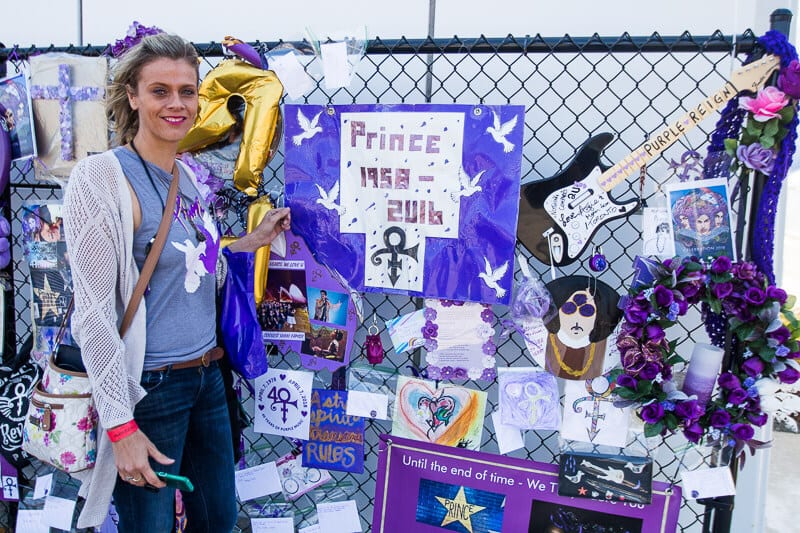 woman beside fence with prince memorabilia on it