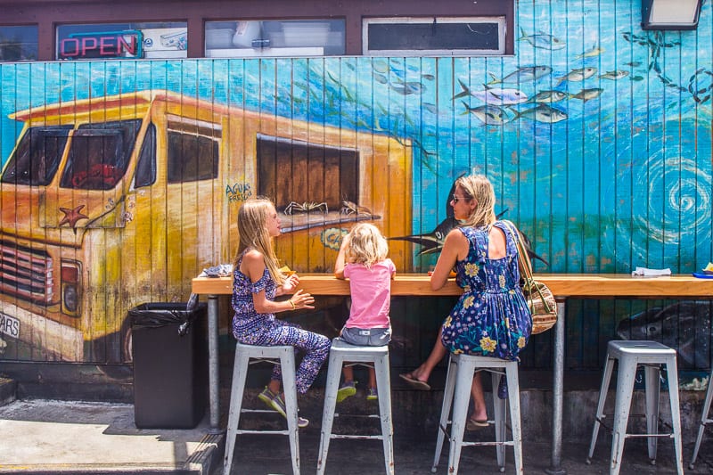  woman andn two girls sitting at countertop in front of a mural of taco truck 
