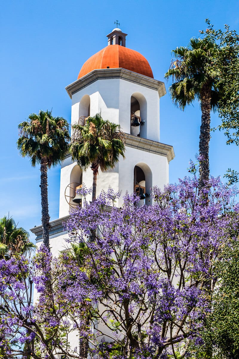 orange domed roof and white tower with purple flowers in front 