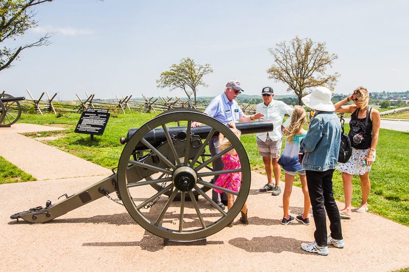 people on tour standing round old artillary gun from civil war
