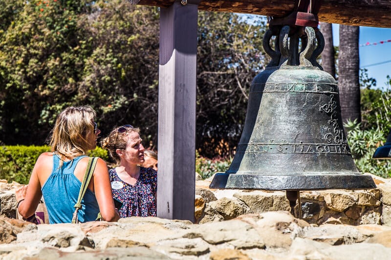 people standing next to a large bell