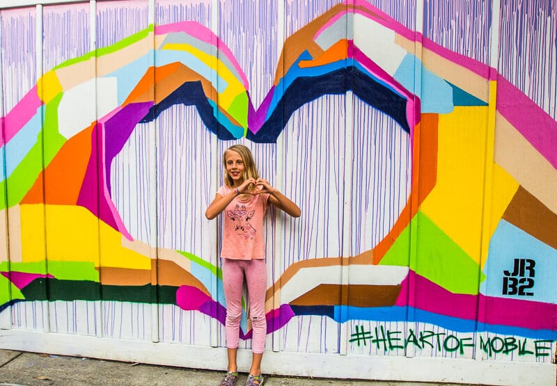 girl standing in front of a wall mural