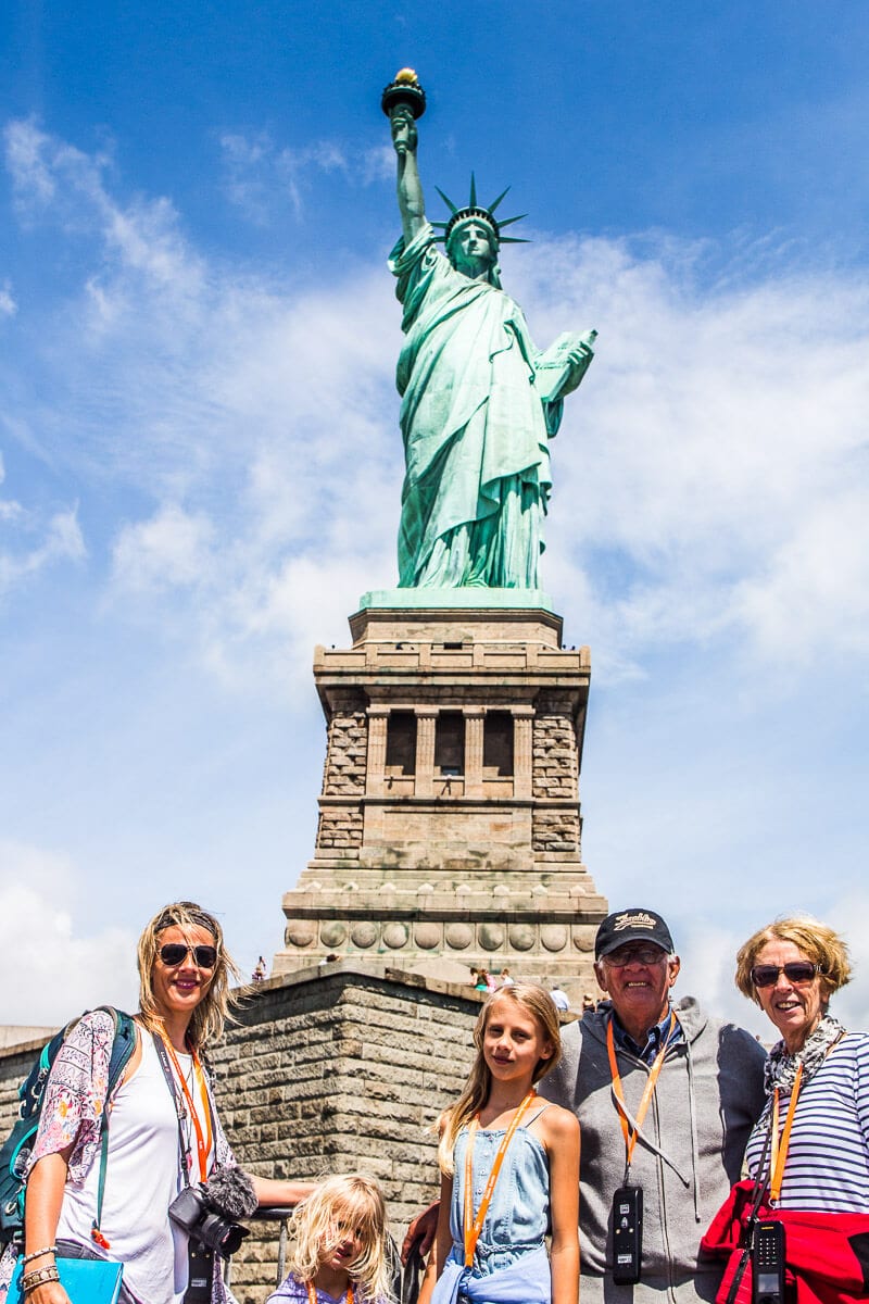 caz and family posing under Statue of Liberty 