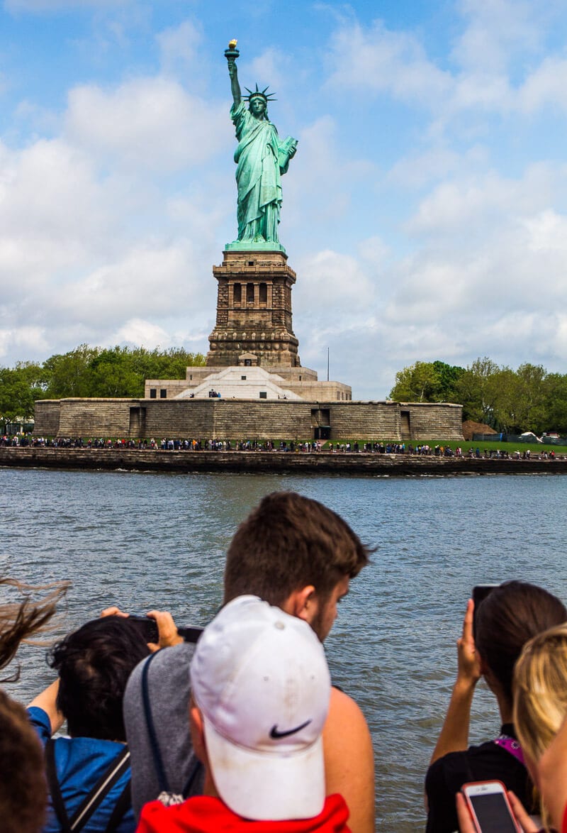 people on ferry looking Statue of Liberty 