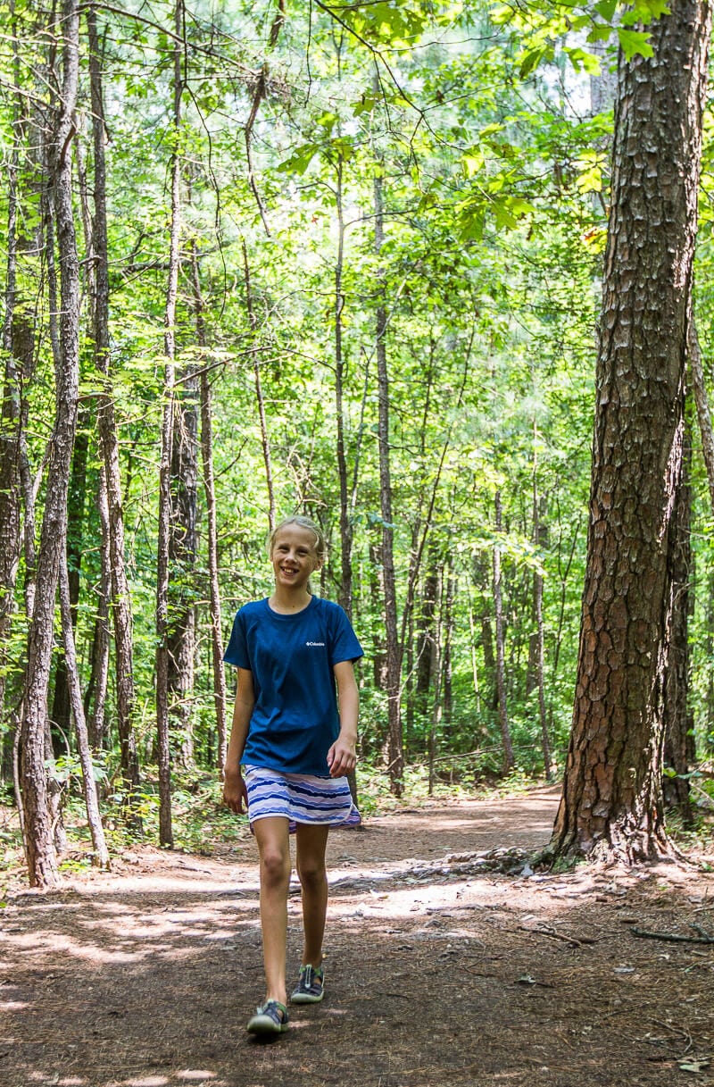 girl walking through a forest trail