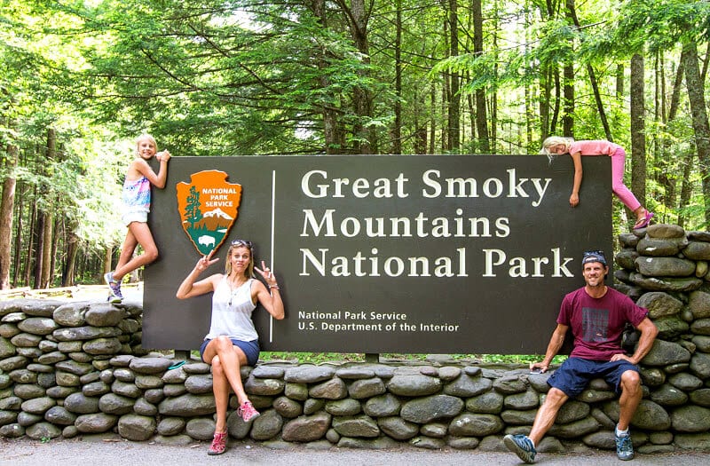 family beside great smoky mountains national park sign