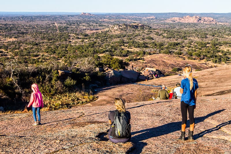 girl and kids sitting on  Enchanted Rock looking at view
