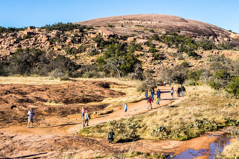 hikers on trail with view of Enchanted Rock 