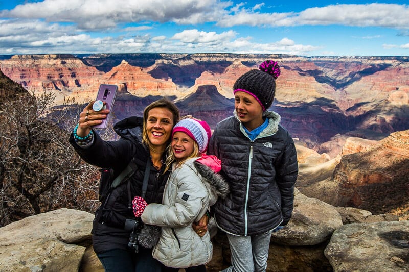 woman and girls posing for camera with views of grand canyon