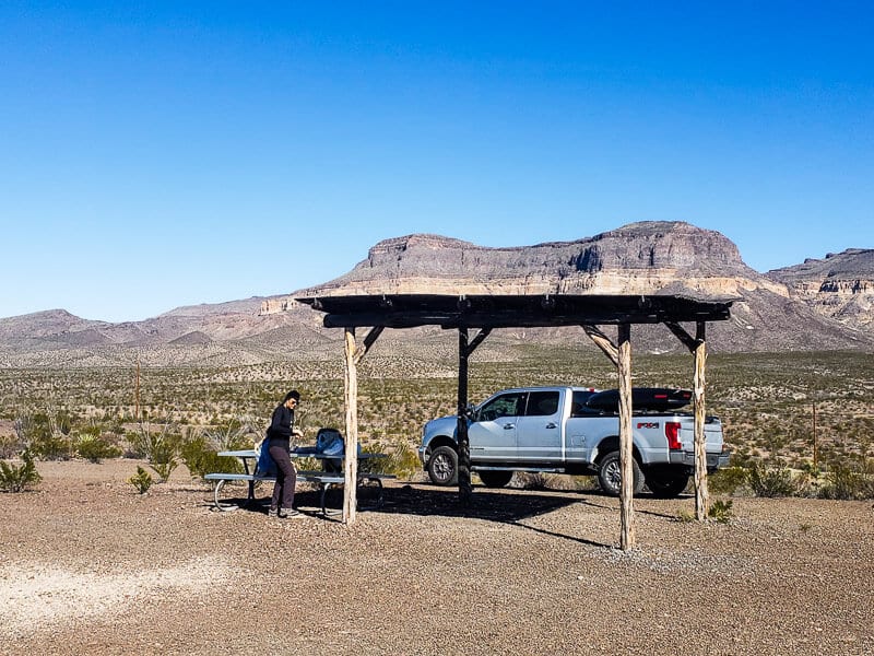 people siting at a picnic table with a mountain in the background
