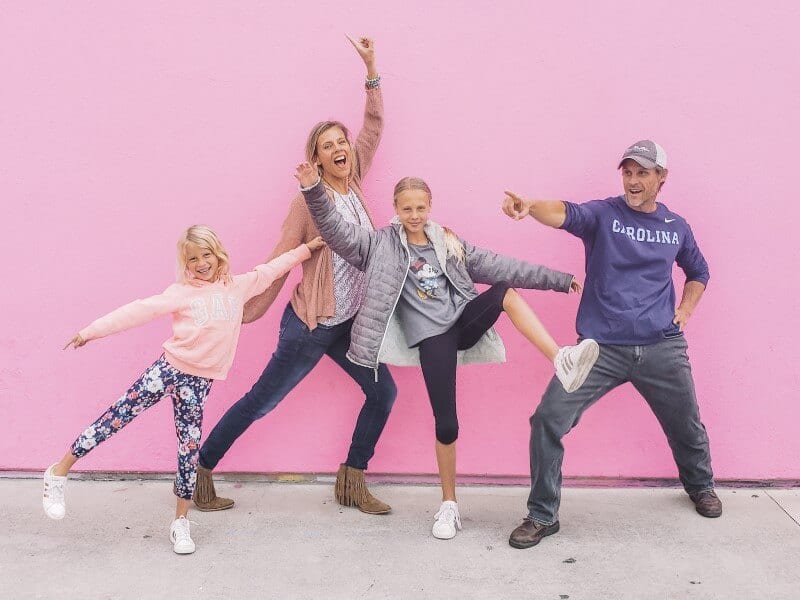 family posing in front of pink wall