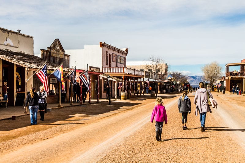 people walking down a dirt road in an old town
