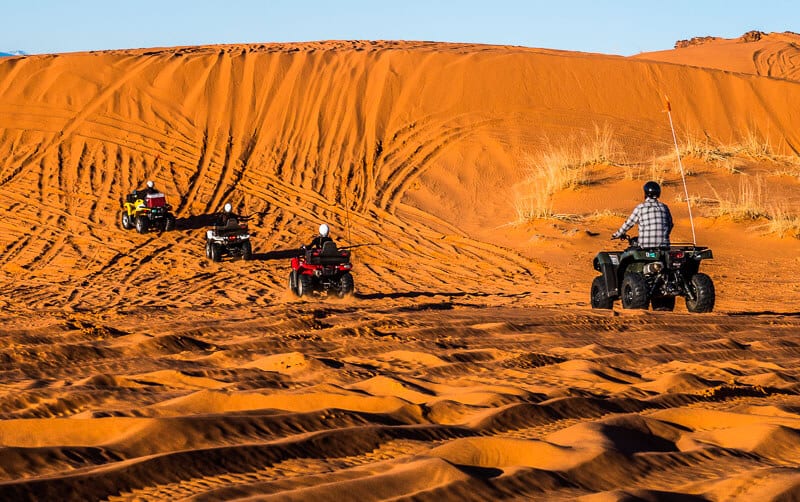 people riding bikes up sand dunes