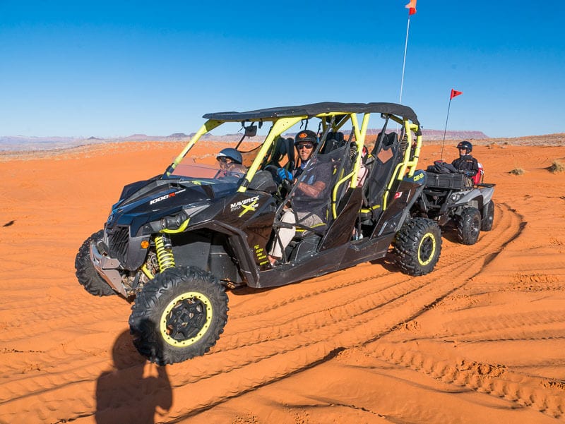 people sitting in an ATV on the sand dunes