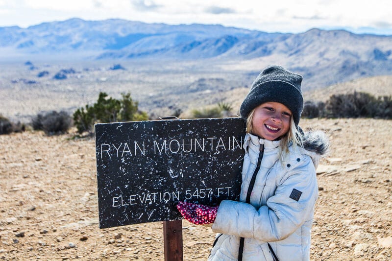 girl next to Ryan Mountain Hike sign at the summit