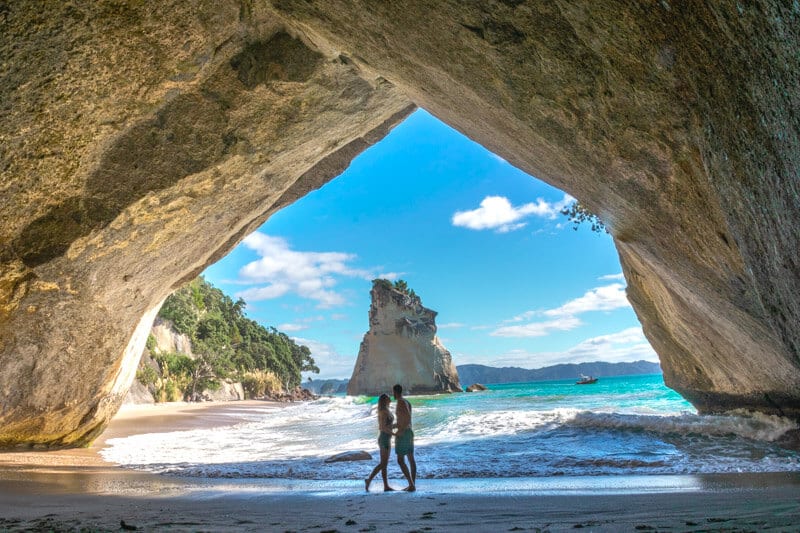 couple hugging in the Cathedral Cove looking at views of water and rocks