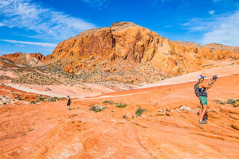 woman talking to camera on the bright orange rocks of valley of fire state park nevada