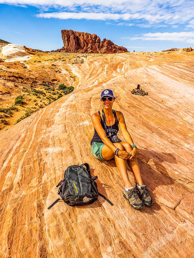 woman sitting on orange rocks posing with red mountain in background