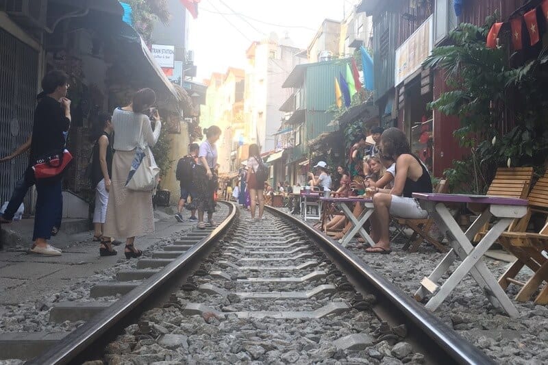 people sitting at tables beside railway line in hanoi