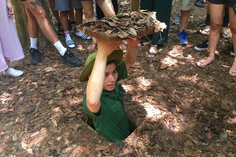 man popping out of Cu Chi tunnels