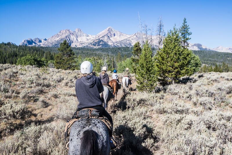 people horse riding with mountains in the background